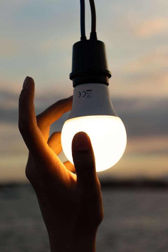 Photo by Amanuel Flores A hand holding a glowing light bulb against a twilight sky, symbolizing ideas and innovation.