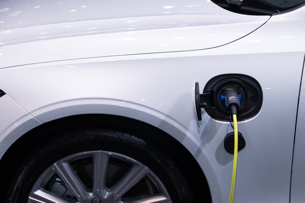 Photo by Rathaphon Nanthapreecha A white electric car is plugged in for charging, close-up view of the charging port.