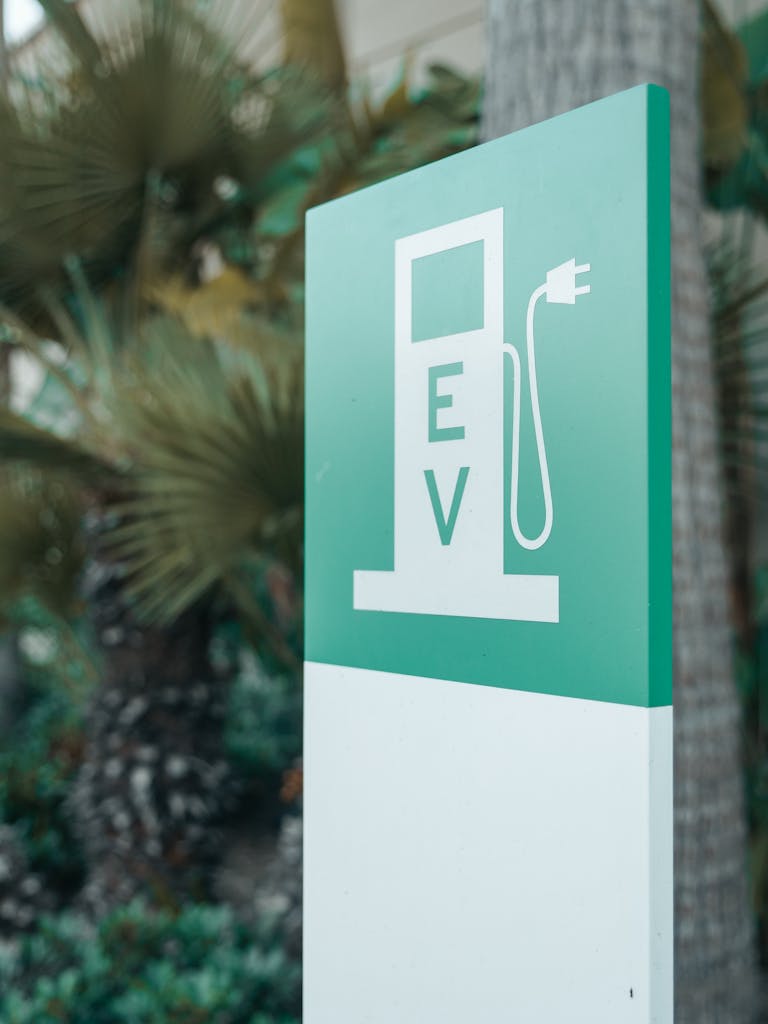 Photo by Kindel Media Close-up of a green and white electric vehicle charging station sign with nature background.
