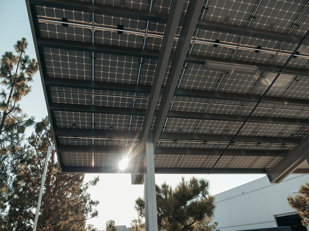 Photo by Kindel Media Low angle shot of solar panels with sun shining through, illustrating renewable energy concept.