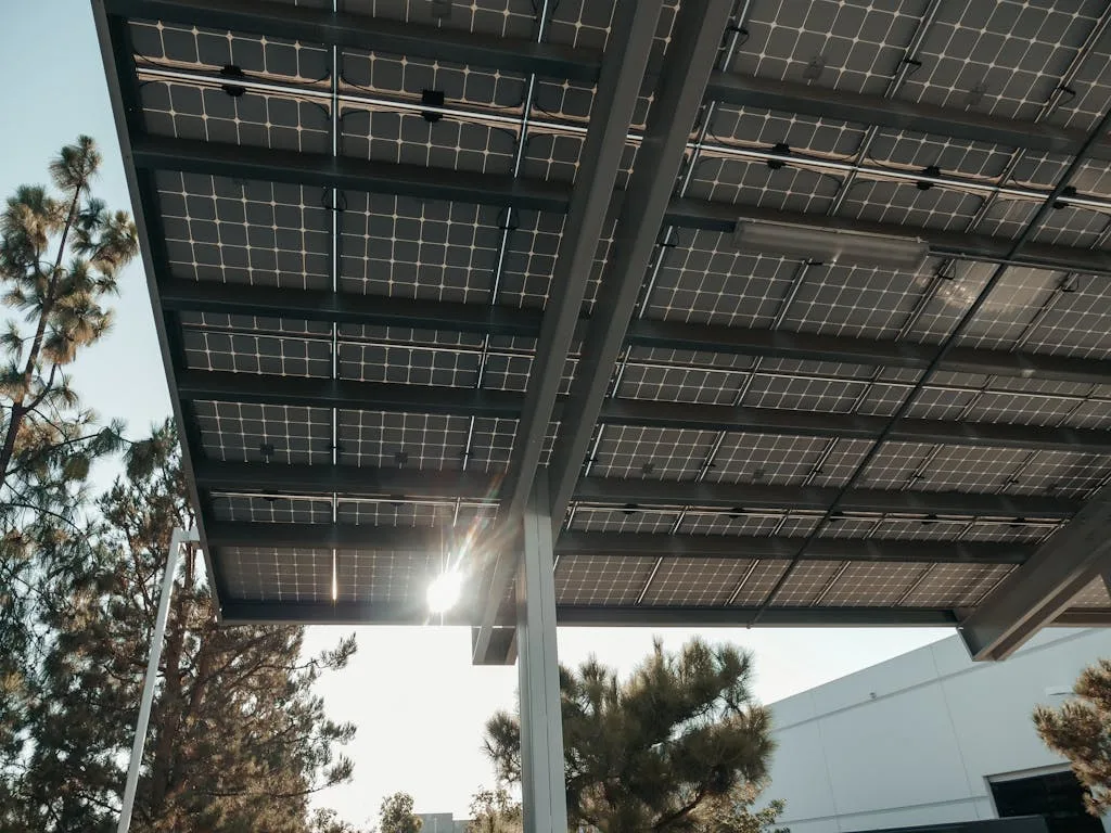 Photo by Kindel Media Low angle shot of solar panels with sun shining through, illustrating renewable energy concept.