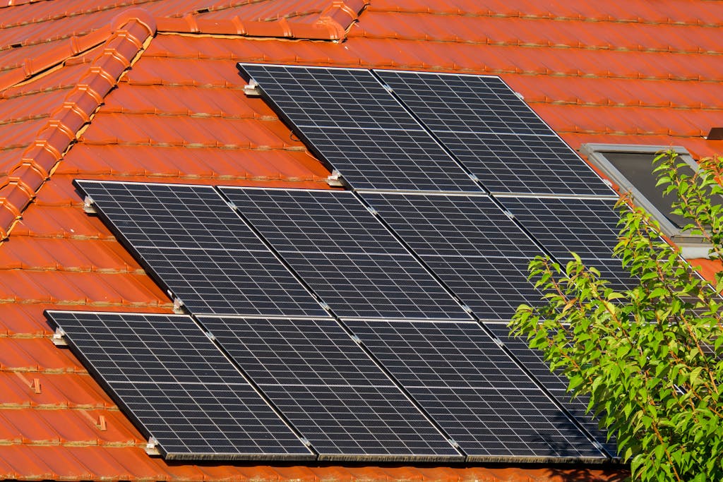 Photo by Vladimir Srajber Close-up of solar panels on a red tiled roof in Croatia, highlighting renewable energy.